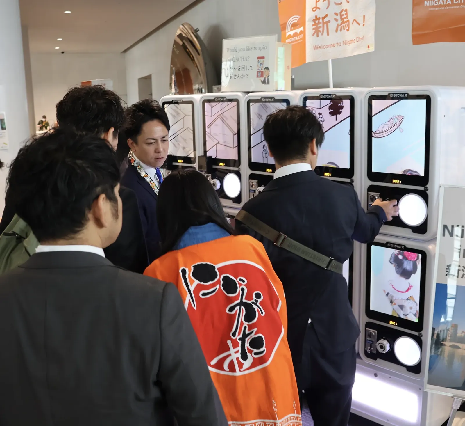 新潟市観光案内所ブースに並ぶデジタルサイネージ搭載ガチャマシン